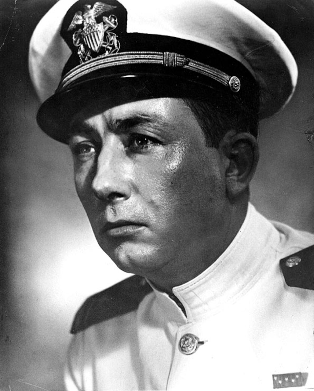 A sailor in uniform poses for a photo.