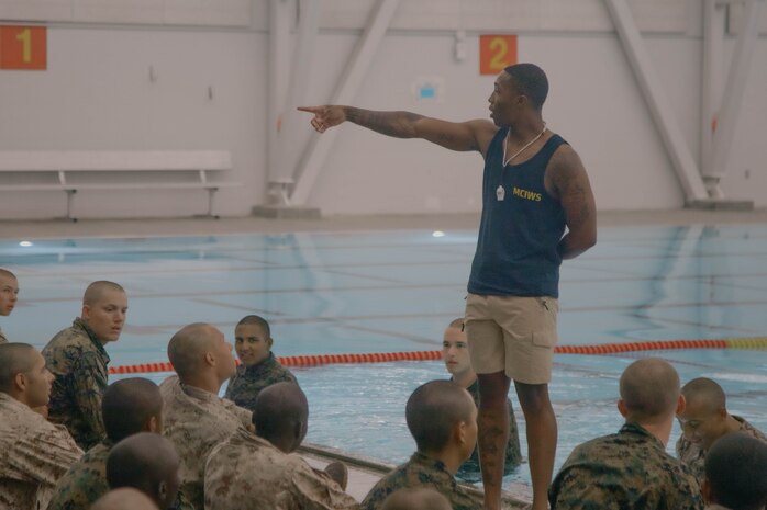 A U.S. Marine Corps instructor of water survival with Support Battalion, Recruit Training Regiment, instructs recruits during a swim qualification event at Marine Corps Recruit Depot San Diego, California, Aug. 13, 2024. The basic swim qualification consists of a 25-meter swim, tower jump into the water, four-minute tread, 25-meter pack swim, and an underwater gear shed. (U.S. Marine Corps photo by Cpl. Elliott A. Flood-Johnson)
