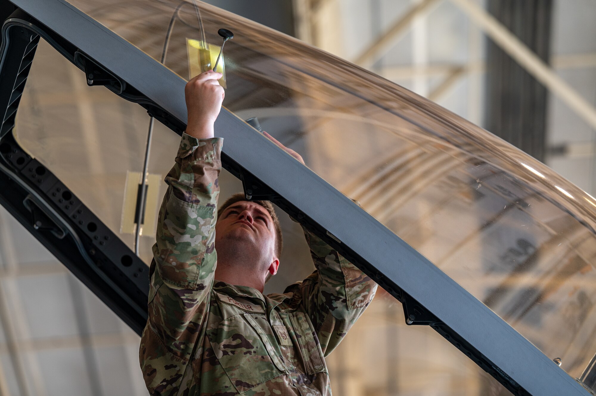 An airman works on a section of an aircraft cockpit