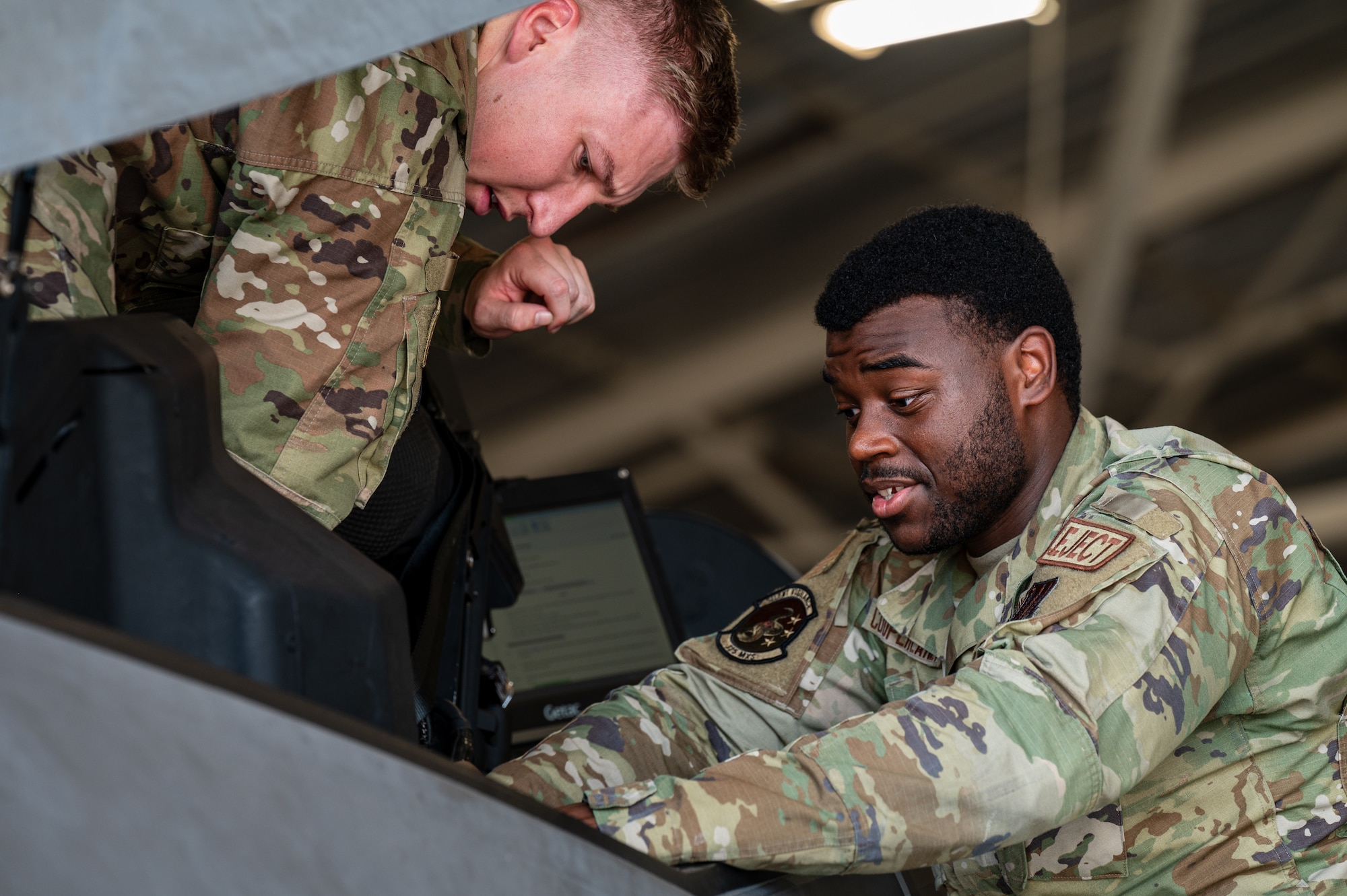Airmen work on the cockpit of an aircraft