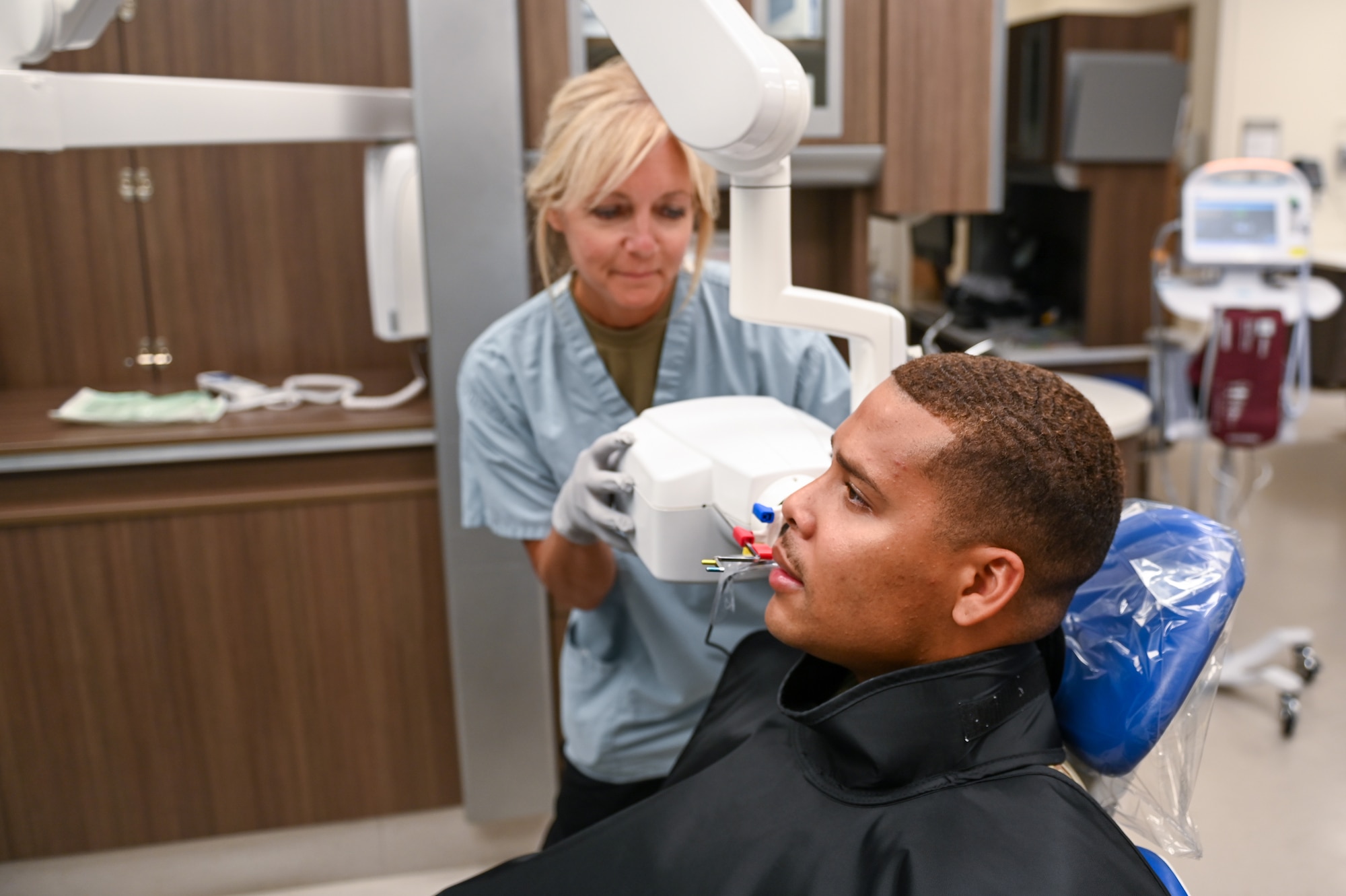U.S. Air Force Master Sgt. Tammy Andrews, a dental assistant assigned to the 115th Fighter Wing, conducts a bite wing X-ray scan on U.S. Army Staff Sgt. Roberto Jauregui assigned to Tripler Army Medical Center July 24, 2024, at Desmond T. Doss Health Clinic on Schofield Barracks Army Base, Hawaii. Airmen assigned to the 115 MDG completed a two-week Medical Facility Annual Training on the island of Oahu to maintain mission readiness. (U.S. Air National Guard photo by Master Sgt. Mary Greenwood)