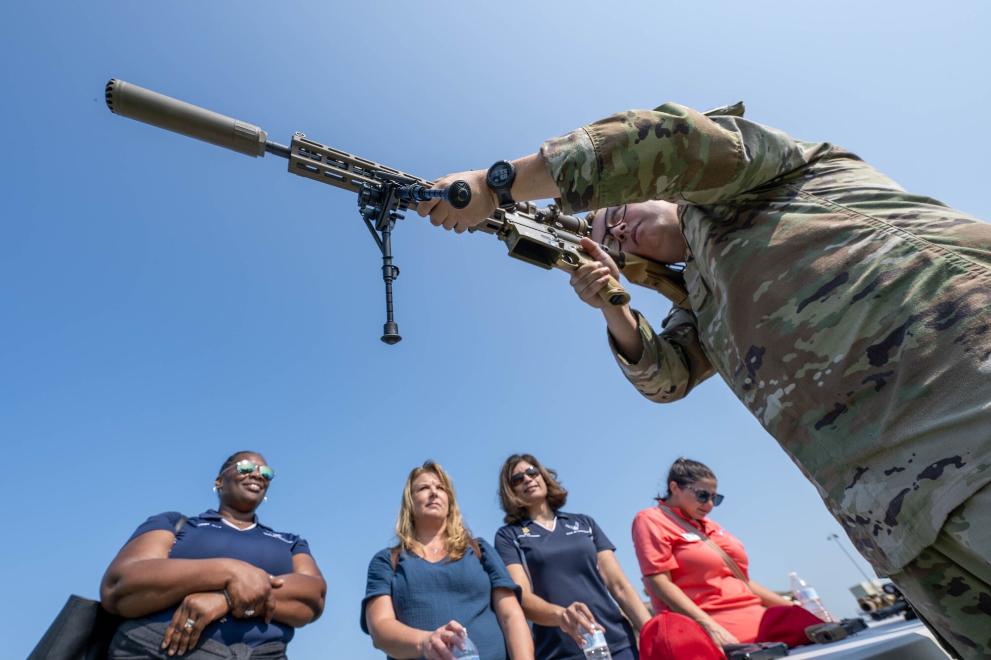 A group of honorary commanders watch as U.S. Air Force Senior Airman Troy Cramer, 436th Security Forces Squadron combat arms instructor demonstrates how to aim an M110A1 Squad Designated Marksman Rifle at Dover Air Force Base, Delaware, Aug. 15, 2024. The HCCs toured various elements of the 436th Mission Support Group to familiarize them with the group's mission and capabilities. (U.S. Air Force photo by Mauricio Campino)