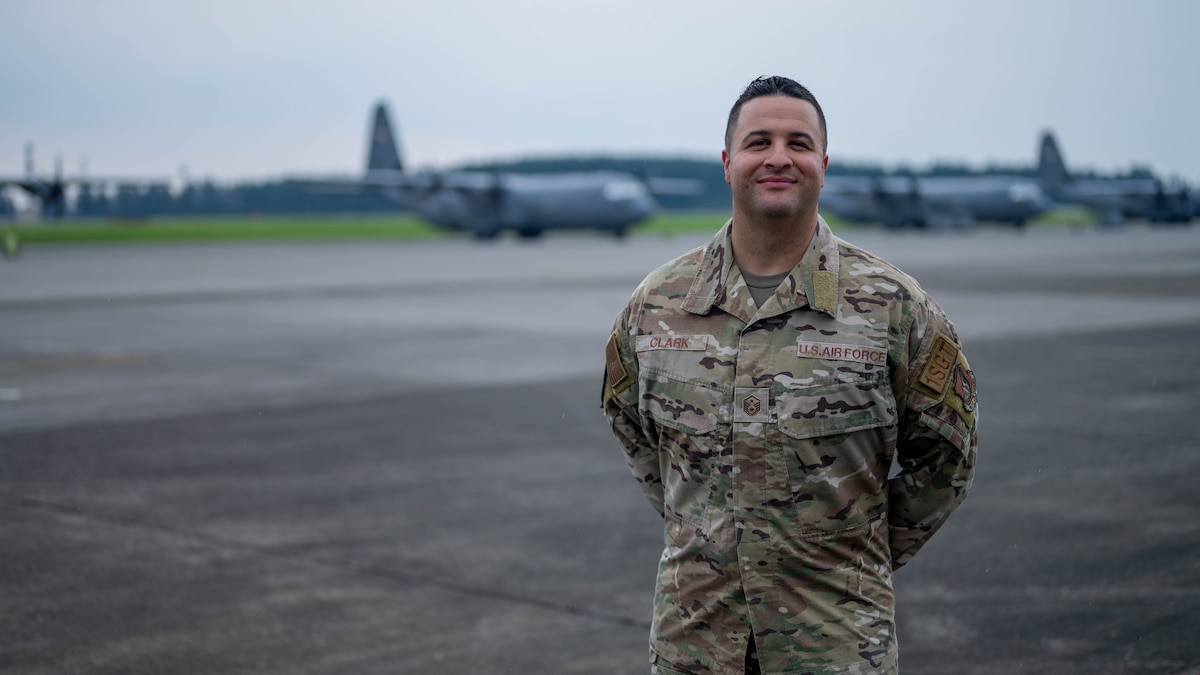 Service member poses in front of planes for photo.