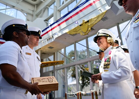 Senior Chief Nevilin Davis assigned to Navy Medicine Operational Training Command presents the outgoing commander, Capt. Kimberly P. Toone with her chief's vessel and charge book as she is made an honorary member of the NMOTC Chief's Mess during a change of command ceremony, Aug. 14. NMOTC as a command oversees six detachments and 12 training centers, with facilities in over 60 locations across the United States. These facilities support training programs in aviation, surface and undersea warfare, expeditionary forces, and special operations, providing medical training for the Navy, other U.S. armed forces, and allied nations. (U.S. Navy photo by Mass Communication Specialist 1st Class Russell Lindsey SW/AW)