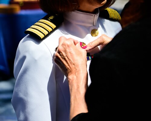 Capt. Nichole Olson is pinned with the Command Ashore pin by her sister during a change of command ceremony for the Navy Medicine Operational Training Command (NMOTC) held aboard Naval Air Station Pensacola, Aug. 14. The Command oversees six detachments and 12 training centers, with facilities in over 60 locations across the United States. These facilities support training programs in aviation, surface and undersea warfare, expeditionary forces, and special operations, providing medical training for the Navy, other U.S. armed forces, and allied nations. (U.S. Navy photo by Mass Communication Specialist 1st Class Russell Lindsey SW/AW)