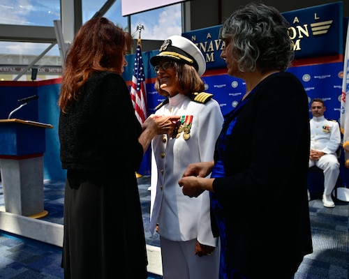 Capt. Nichole Olson is pinned with the Command Ashore pin by her sister during a change of command ceremony for the Navy Medicine Operational Training Command (NMOTC) held aboard Naval Air Station Pensacola, Aug. 14. The Command oversees six detachments and 12 training centers, with facilities in over 60 locations across the United States. These facilities support training programs in aviation, surface and undersea warfare, expeditionary forces, and special operations, providing medical training for the Navy, other U.S. armed forces, and allied nations. (U.S. Navy photo by Mass Communication Specialist 1st Class Russell Lindsey SW/AW)