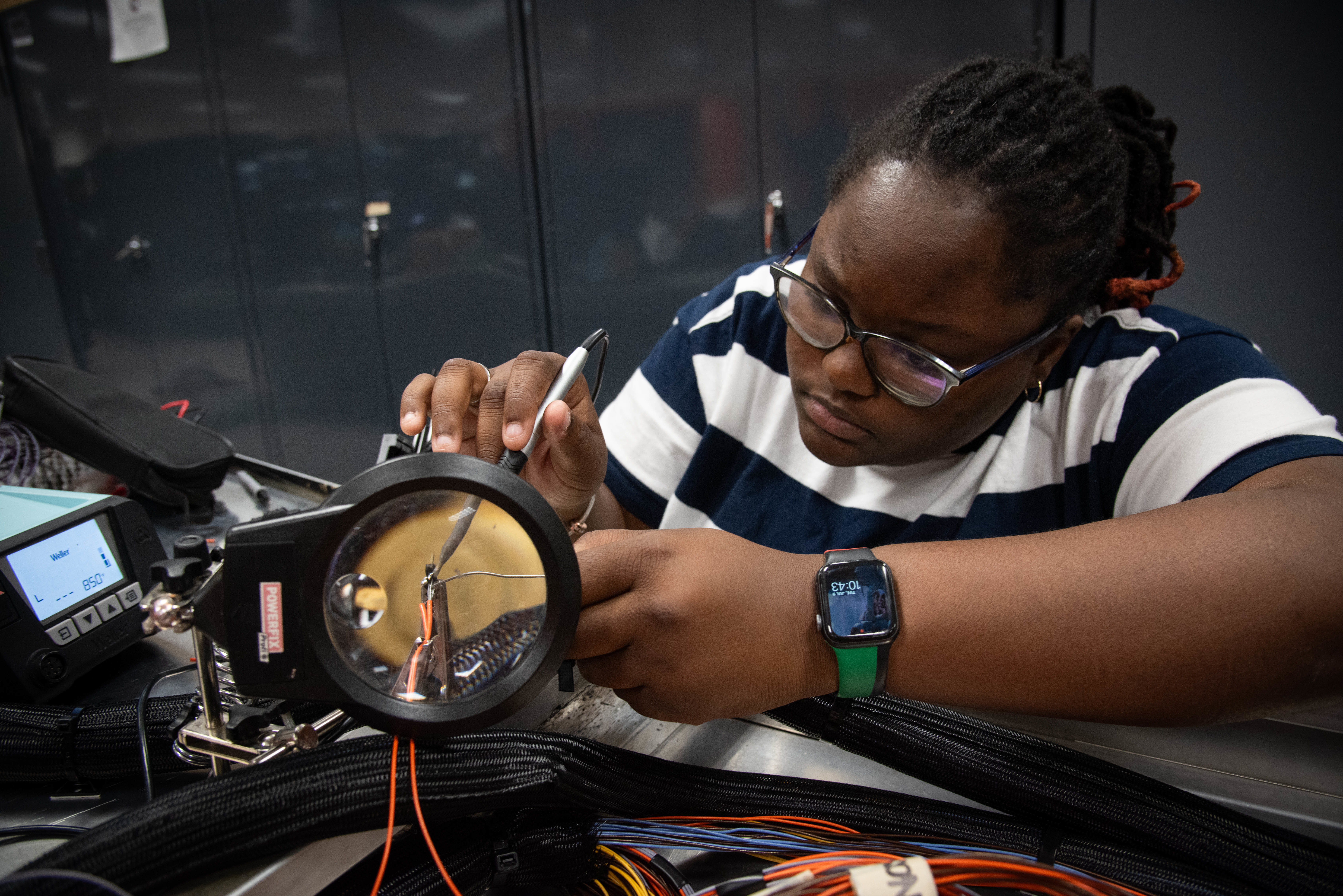 Naval Information Warfare Center (NIWC) Atlantic student intern Santi Gilliard solders wiring on an Airfield Lighting Display board. NIWC hosted 94 talented student interns this summer in support of continued learning in STEM and furthering innovation in the information warfare battlespace. Interns got hands-on experience in multiple areas installation and integration of software, cyber operations development for mobile devices, server configuration, vulnerability testing and more. The NIWC Atlantic Student Intern program is designed to provide an internship for students currently enrolled in school at a collegiate level. Students follow a developmental plan that provides a roadmap for potential future employment at NIWC Atlantic.