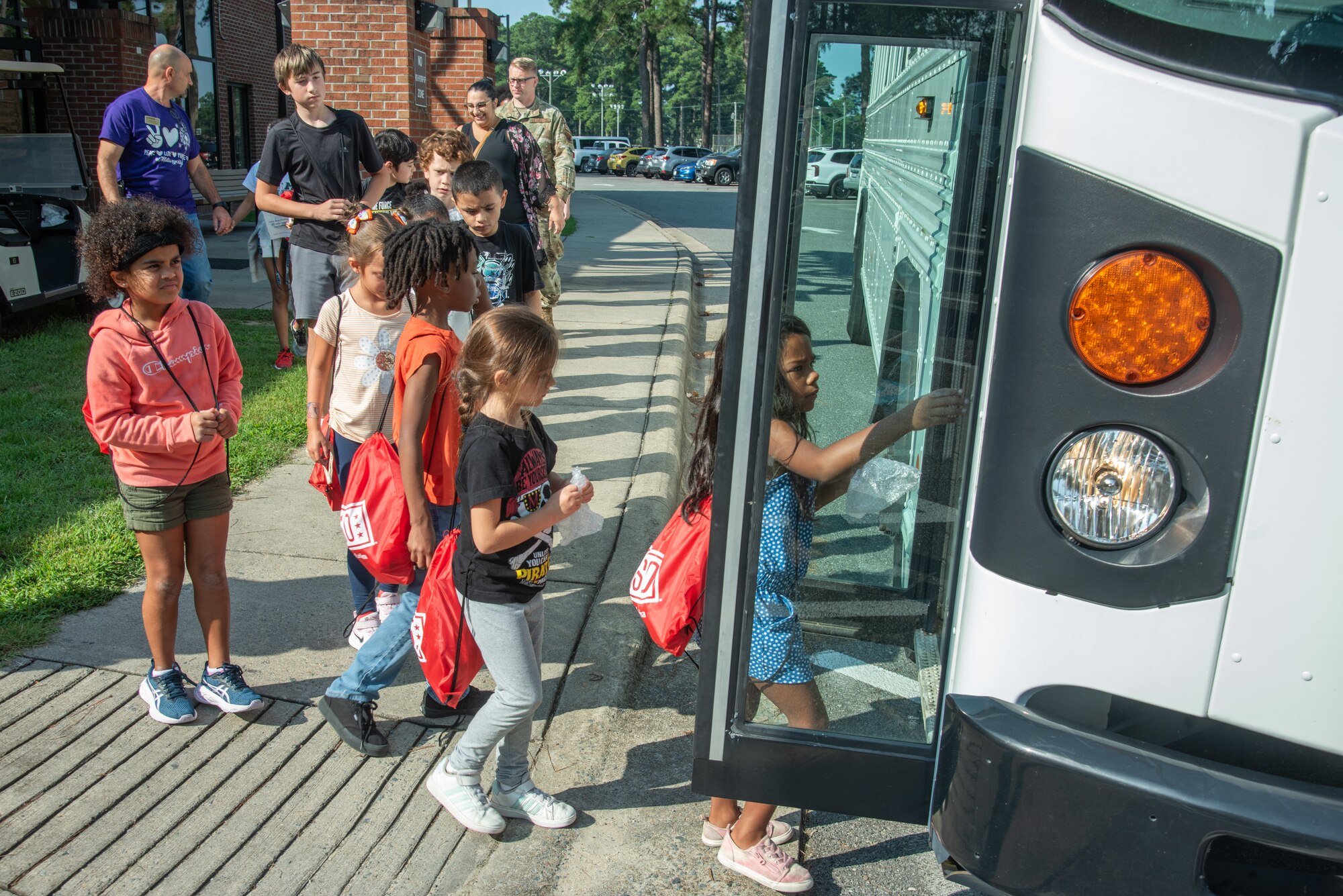 Children of service members walk toward a bus for travel to a pre-deployment function line during an “OPERATION Bug Out” kids’ mock deployment.