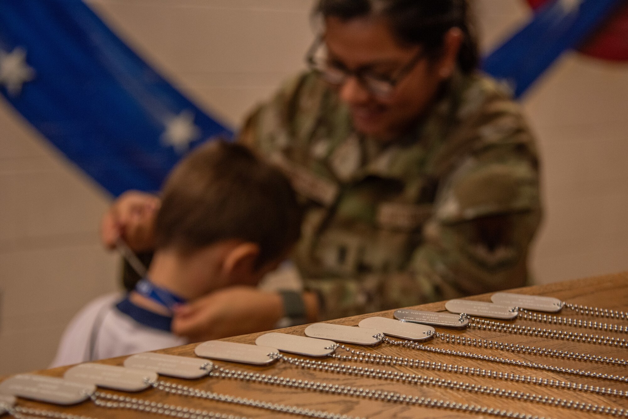 Children of service members receive mock dog tags during an “OPERATION Bug Out” kids’ deployment.