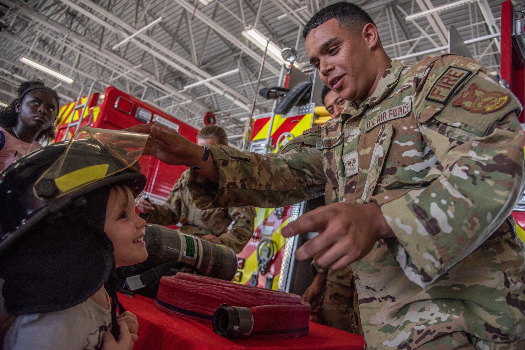 SrA Marwane Hsaini, 4th CES firefighter, places a helmet on a military child dependent during an OPERATION Bug Out ‘kids’ deployment.