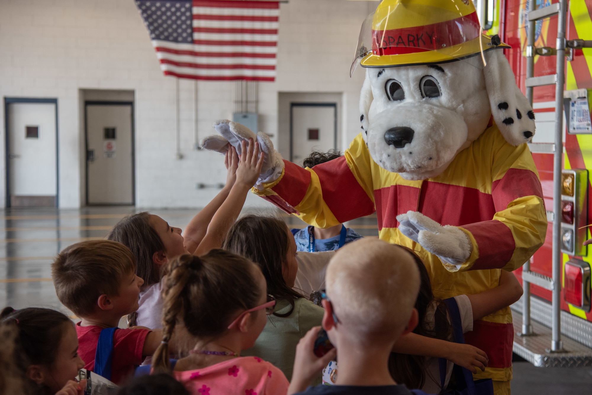 Children of service members greet Sparky the Fire Dog during an “OPERATION Bug Out” kids’ deployment.
