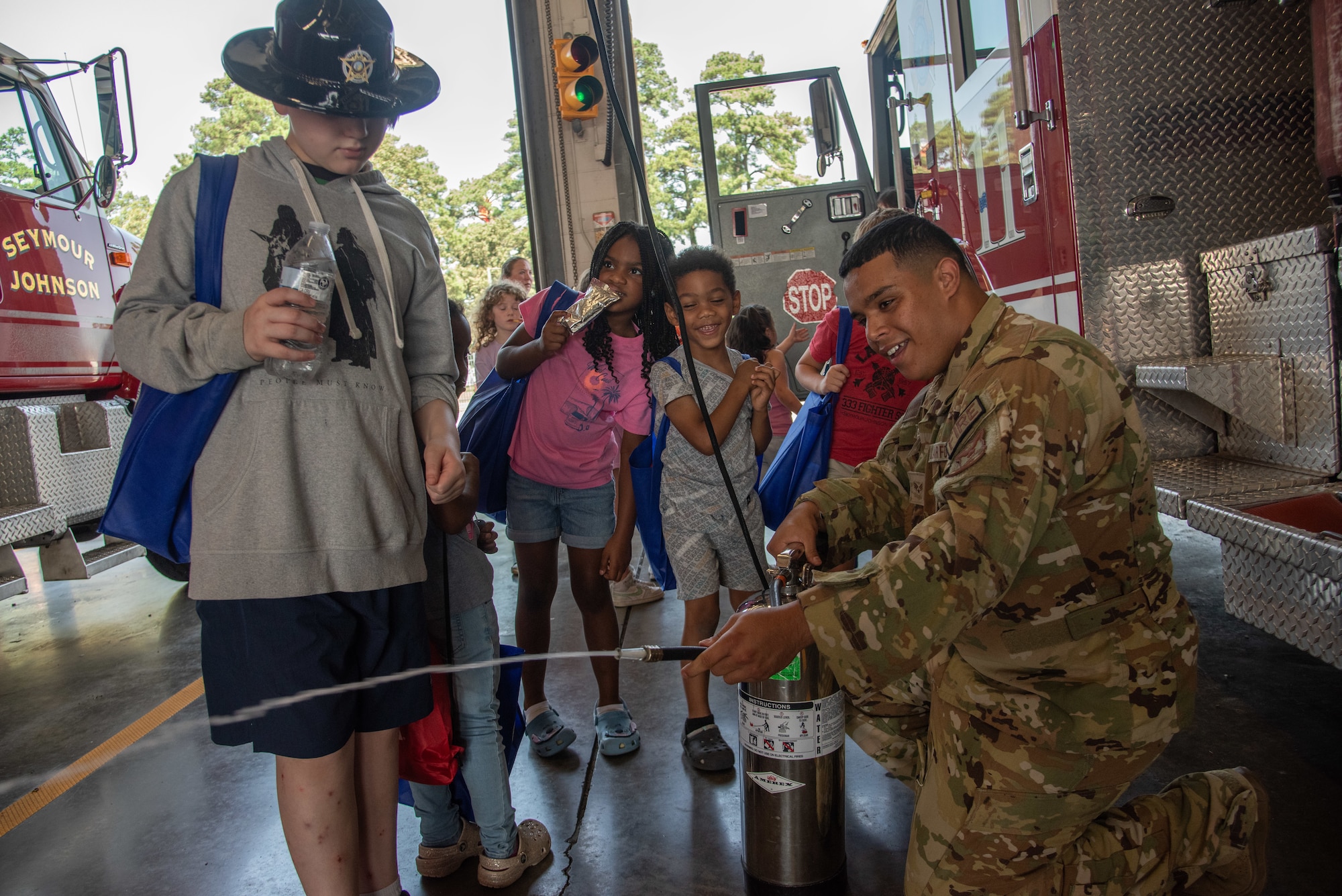 SrA Marwane Hsaini, 4th CES firefighter, shows children of service members firefighting equipment during an “OPERATION Bug Out” kids’ deployment.