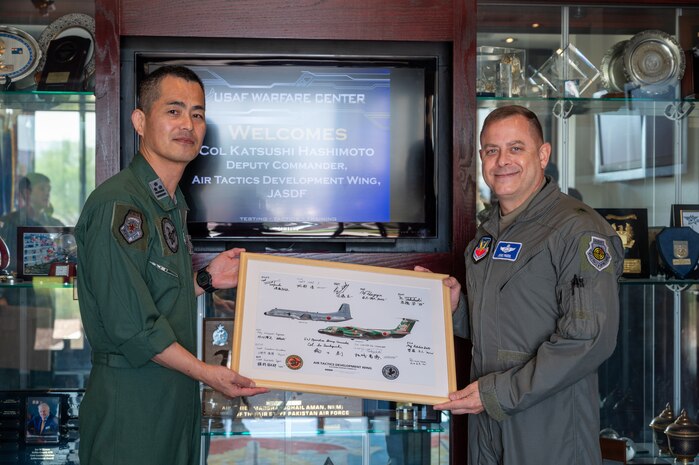 Japan Air Self Defense Force and U.S. Air Force Warfare Center Airmen pose for a photo holding a gift