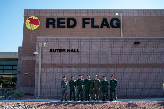 Delegation from the Japanese Air Self Defense Force and commander of 414th Combat Training Squadron pose for a group photo in front of Red Flag building