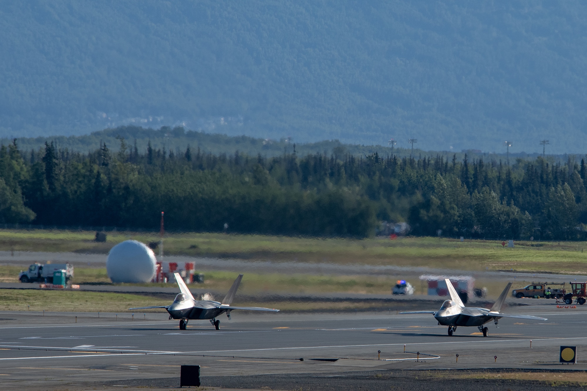 Two F-22 Raptors taxi on a runway at Joint Base Elmendorf-Richardson, Alaska