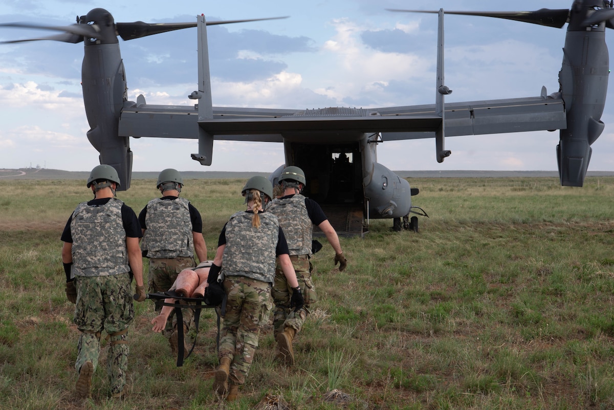U.S. Airmen carry a mannequin to a CV-22 Osprey tiltrotor aircraft assigned to the 20th Special Operations Squadron during exercise Medic Rodeo at Melrose Air Force Range, New Mexico, Aug. 13, 2024. The four-day exercise involved 18 teams from across the Air Force competing against each other to test their practical combat casualty care training. (U.S. Air Force photo by Staff Sgt. Kevin Williams)