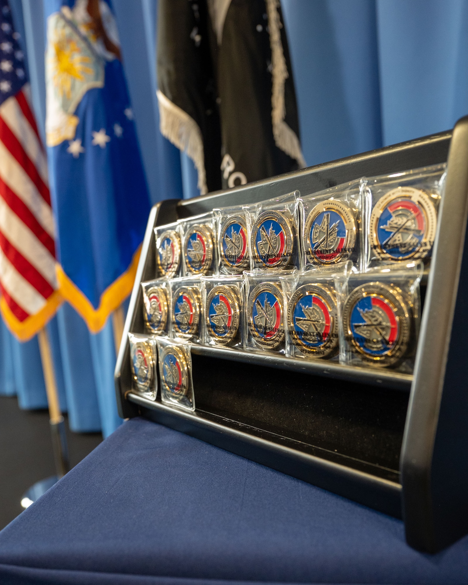 A collection of the coveted coins with the United States Air Force Honor Guard seal sits atop a display table at an Honor Guard technical training school graduation ceremony