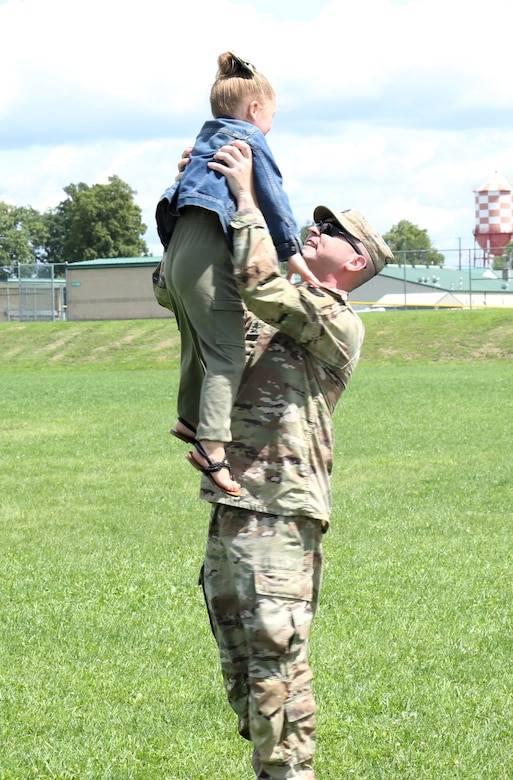 U.S. Army Sgt. 1st Class Kurtis Startzel with the 56th Stryker Brigade Combat Team, 28th Infantry Division, Pennsylvania Army National Guard smiles while lifting his daughter sky-high at the unit's pre-deployment farewell ceremony at Fort Indiantown Gap, Aug. 21, 2024.