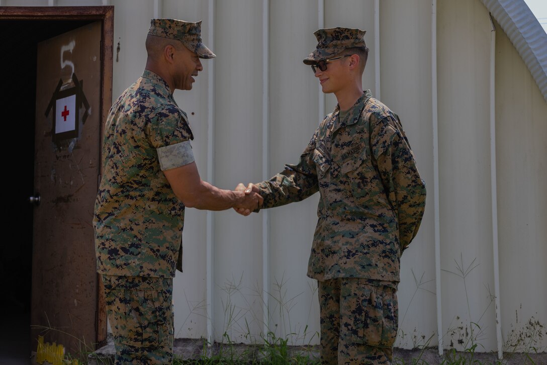 U.S. Marine Corps Lt. Gen. Calvert L. Worth Jr., commanding general of II Marine Expeditionary Force, left, awards a challenge coin to Lance Cpl. Jose Benitez-Urquia, a food service specialist with II MEF Support Battalion, II MEF Information Group, during a II MEF exercise at Marine Corps Auxiliary Landing Field, Bogue, North Carolina, Aug. 15, 2024. The purpose of the exercise is to provide II Marine Expeditionary Force the opportunity to rehearse command and control capabilities in a tactical environment. (U.S. Marine Corps photo by Lance Cpl. Alexander Hires)