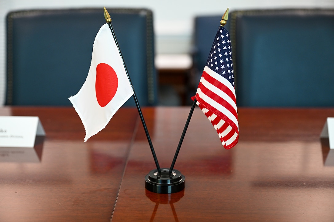 Small versions of the American and Japanese flags sit next to each other  on a conference room table.