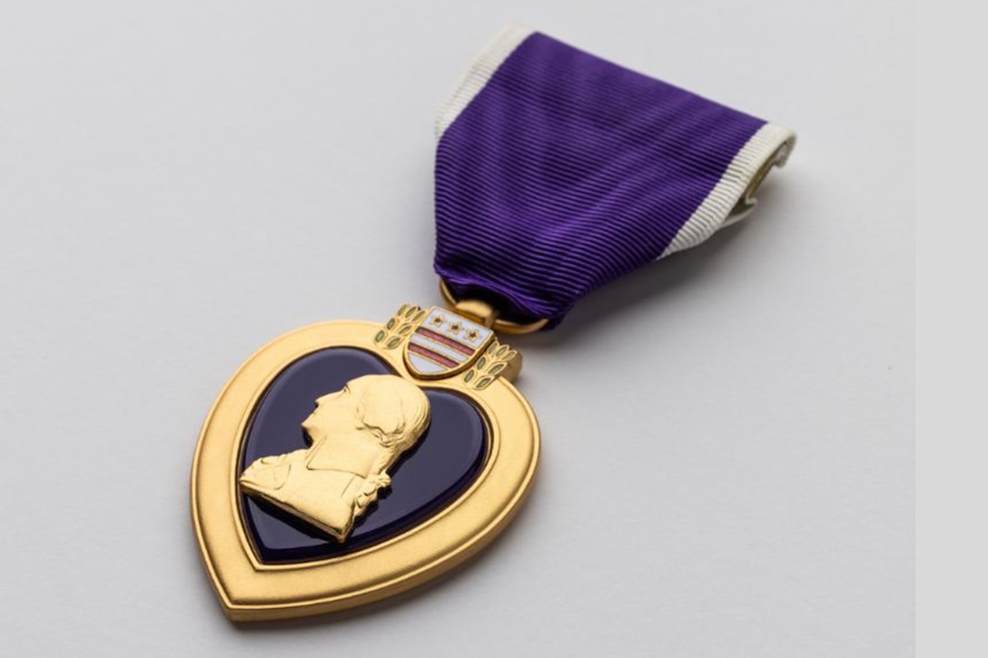 View of a purple ribbon attached to a heart-shaped medal with a likeness of George Washington's profile in the center.