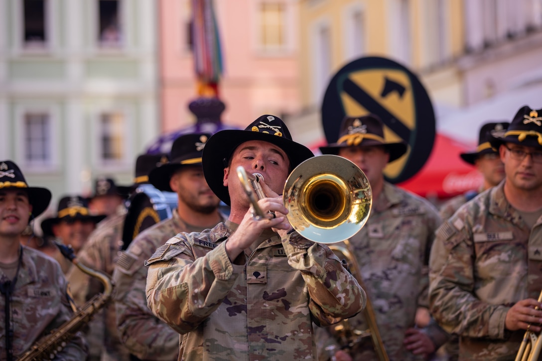 A soldier plays a trombone as other band members watch during a parade.