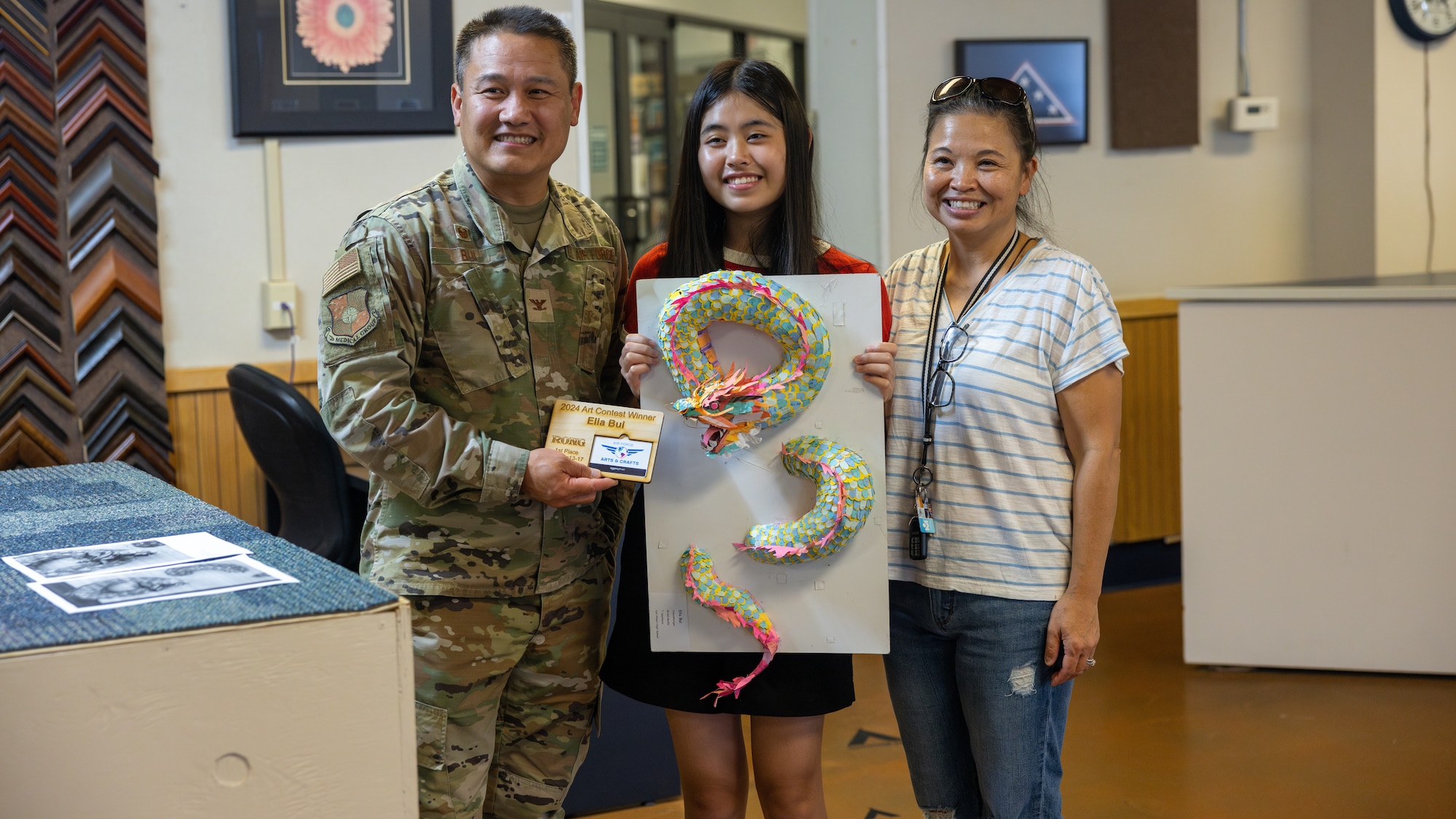 Ella Bui, contest winner, with her mother, her father and art sculpture.