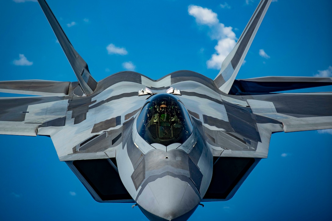 A close-up of an airman flying an aircraft in a blue sky.