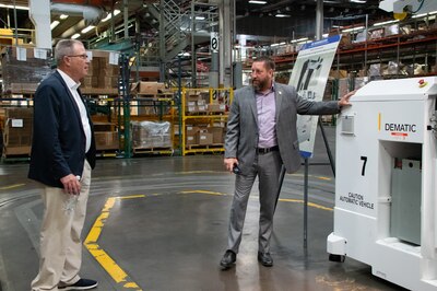 Two men talk as one points to a piece of warehouse equipment