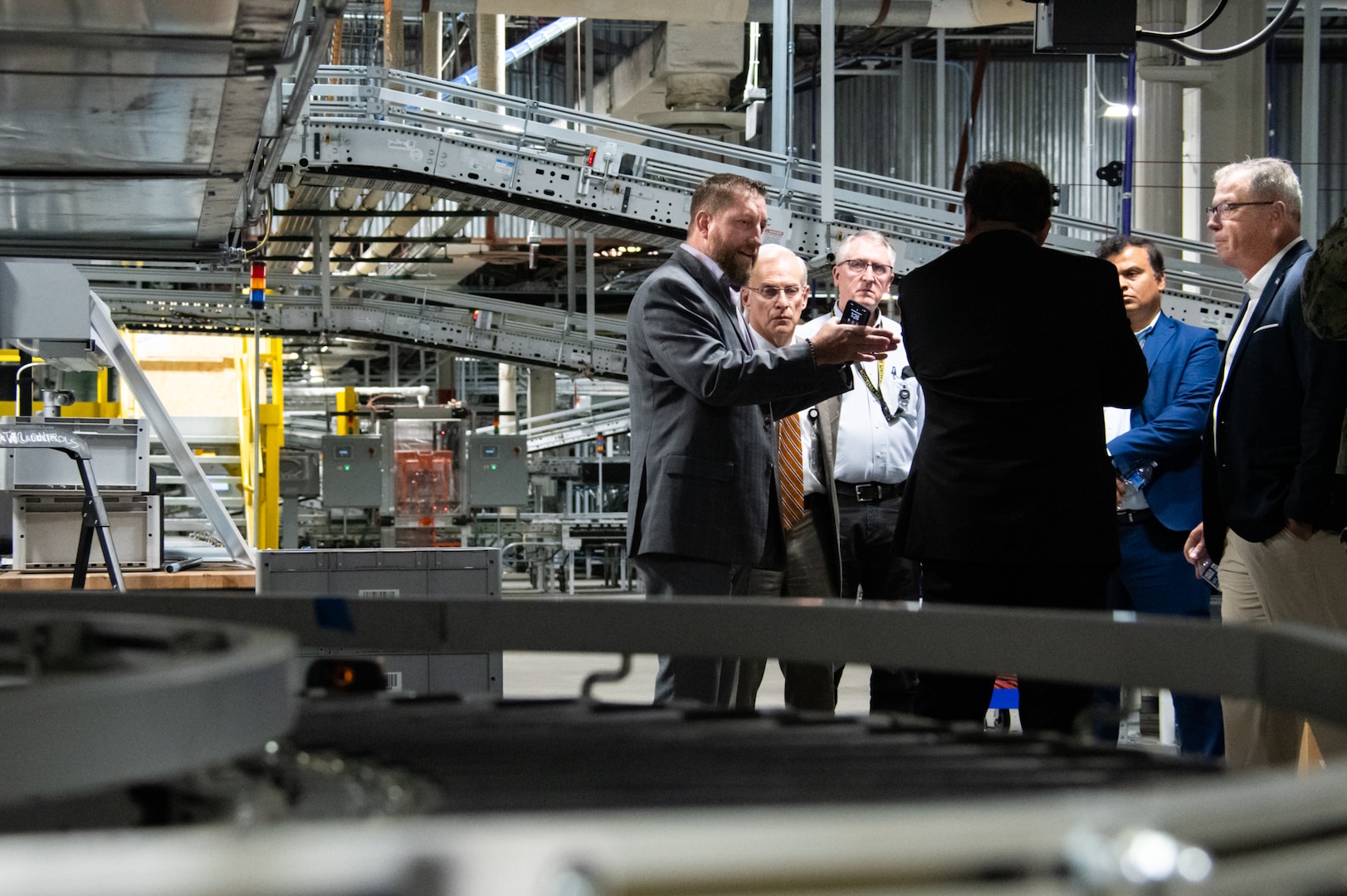 Five men talk surrounded by warehouse equipment