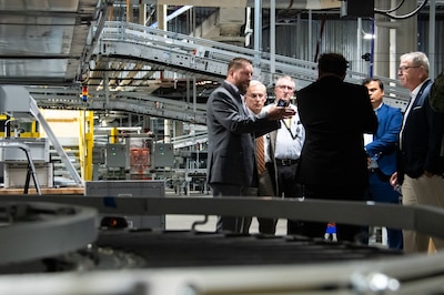 Five men talk surrounded by warehouse equipment