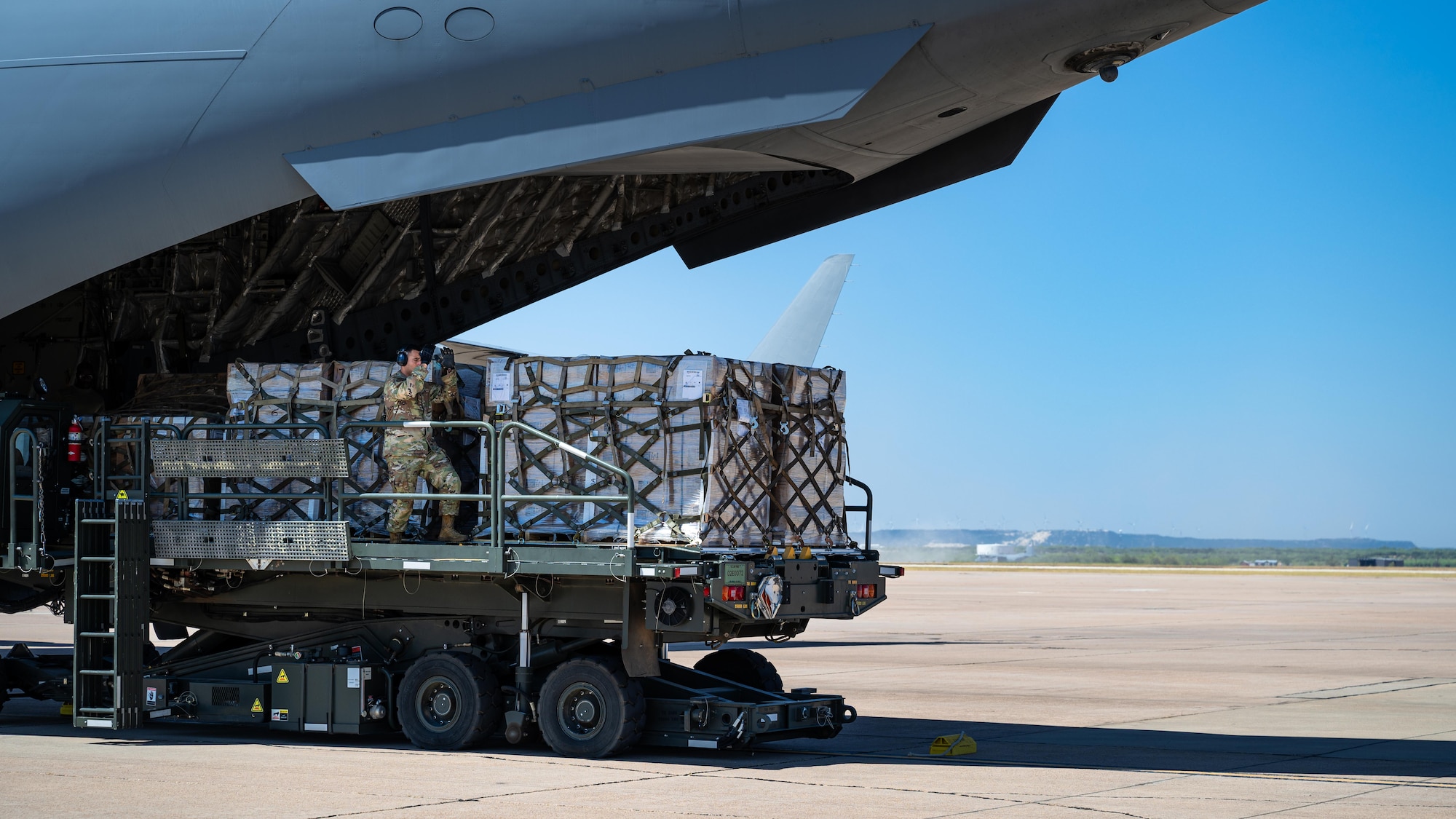 U.S. Air Force Master Sgt. Joshua Greenbaum, 7th Logistics Readiness Squadron air terminal function superintendent, guides humanitarian cargo to a C-17 Globemaster from the 89th Airlift Squadron, Wright-Patterson Air Force Base, Ohio, at Dyess Air Force Base, Texas, Aug. 12, 2024. The 7th LRS partnered with the Denton Program to help deliver 40,000 pounds of rice to the Dominican Republic, where the aid will be distributed to communities in need. Humanitarian relief missions empower the 7th LRS to impact developing nations through versatile logistic support. (U.S. Air Force photo by Airman 1st Class Jade M. Caldwell)