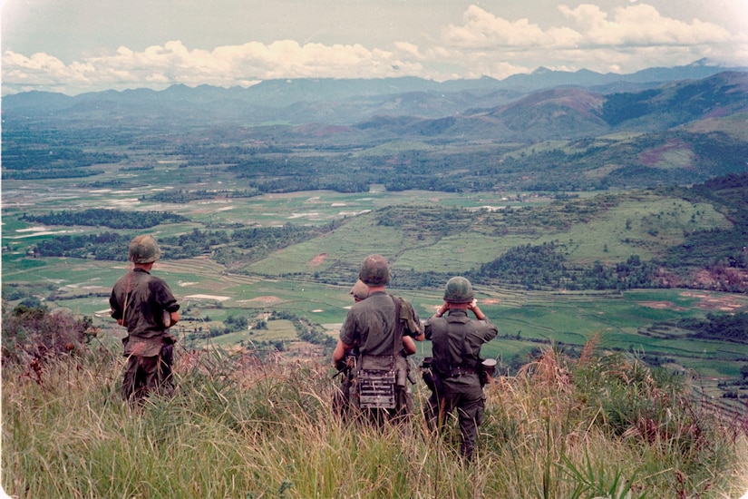 Four men look toward a rolling hillside