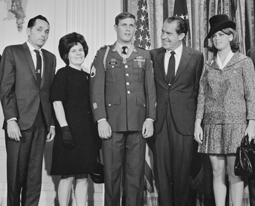 Five people stand on a stage, posing for a photo.