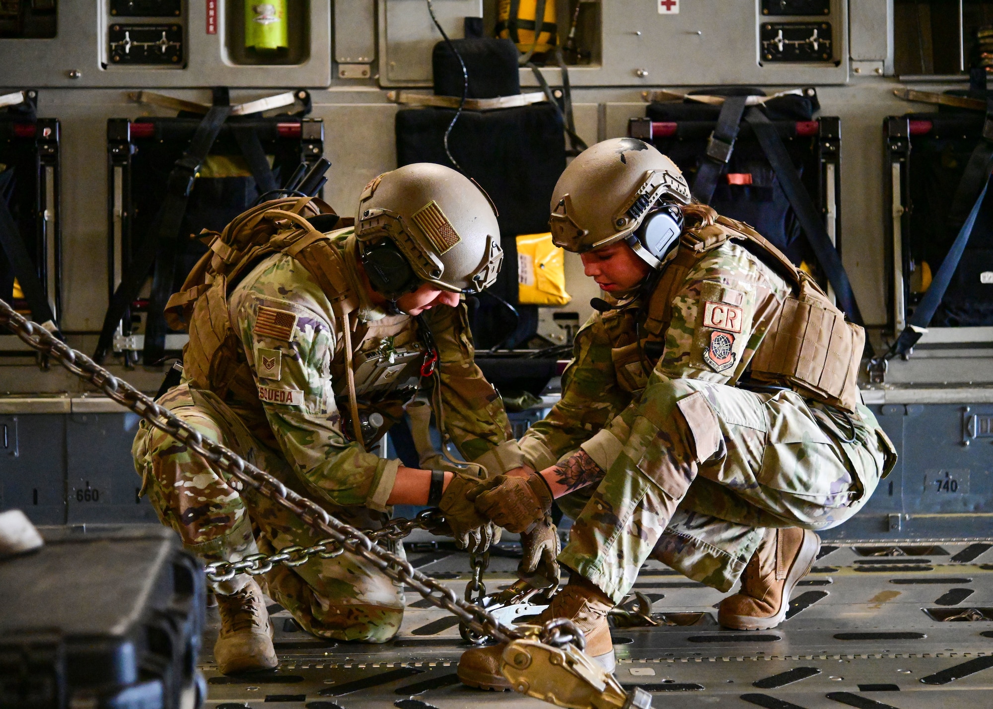 Two service members secure cargo on aircraft.