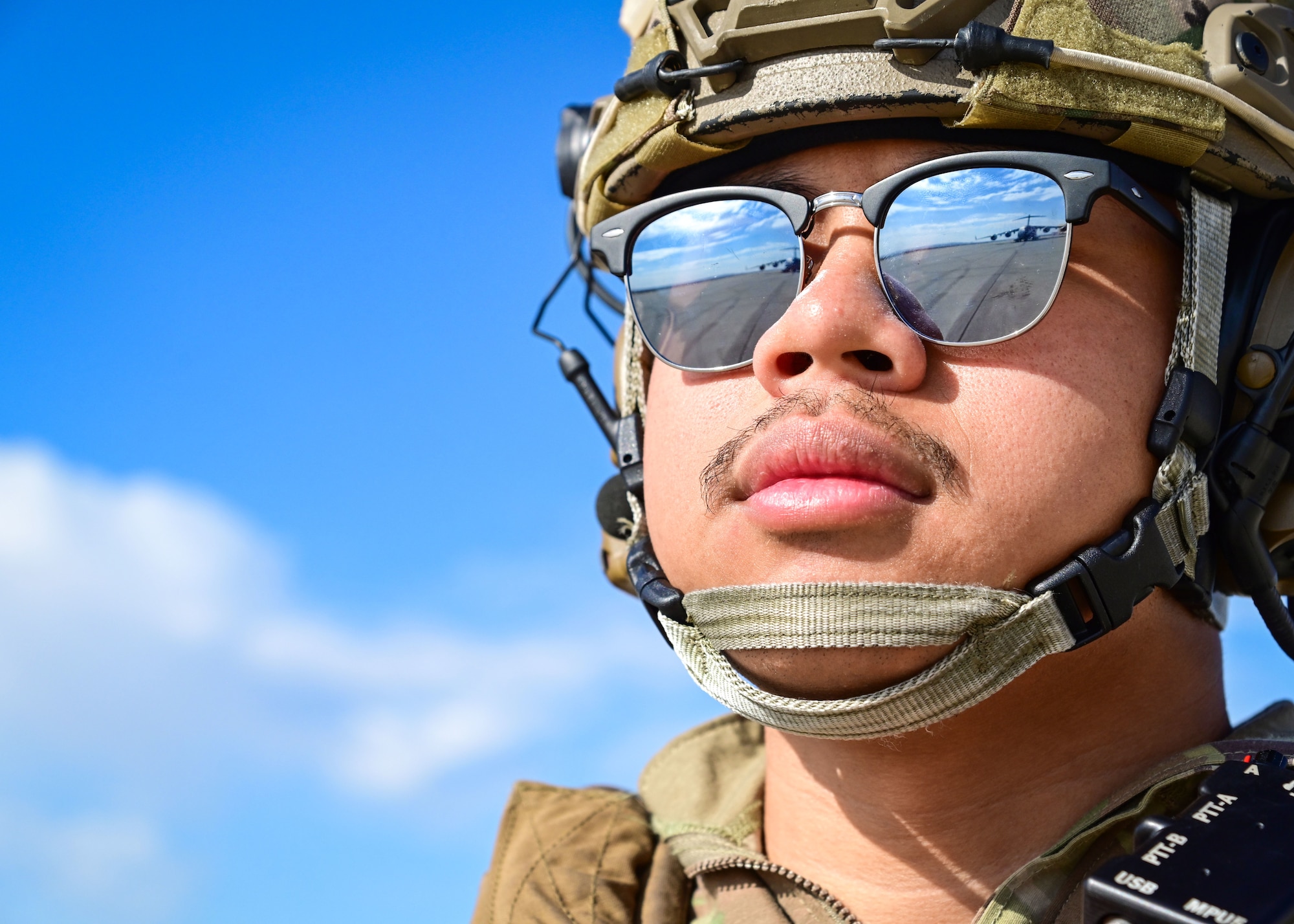 Man looks at aircraft seen in reflection of his sunglasses.