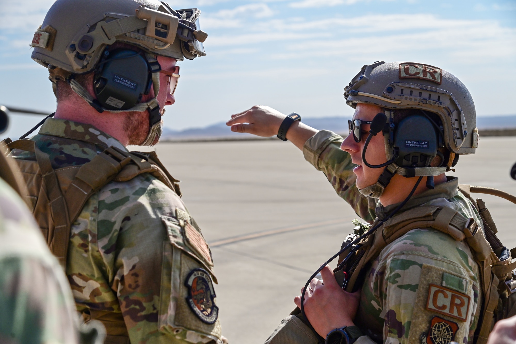 Two service members speak on flightline.