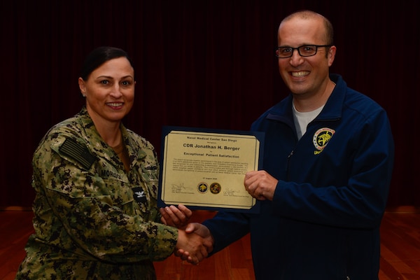 U.S. Navy Capt. Marcy Morlock, executive officer of Naval Medical Center San Diego, left, presents a joint outpatient experience survey 100% satisfaction award to Cmdr. Jonathan Berger, right, during an awards presentation at NMCSD, Aug. 7, 2024. The mission of NMCSD is to provide a superior experience for our staff, patients, and warfighters by delivering exceptional care afloat and ashore. NMCSD employs more than 5,000 active-duty military personnel, civilians, and contractors in southern California to be the preferred choice and leader in compassionate and innovative healthcare. Anchored in excellence, committed to health! (U.S. Navy photo by Mass Communication Specialist 2nd Class Celia Martin)