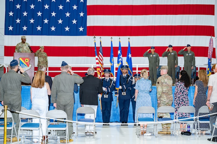 Airman singing national anthem while honor guard posts the colors
