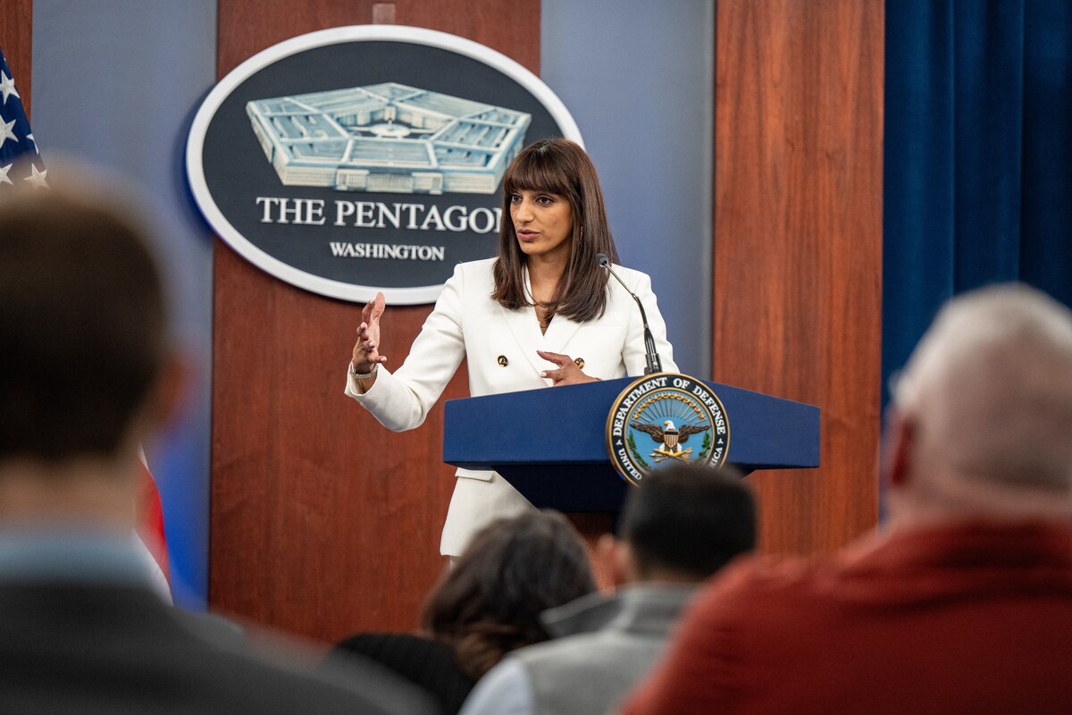 A civilian speaks from a podium to an audience.