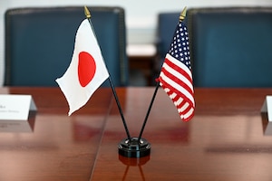 Small versions of the American and Japanese flags sit next to each other  on a conference room table.