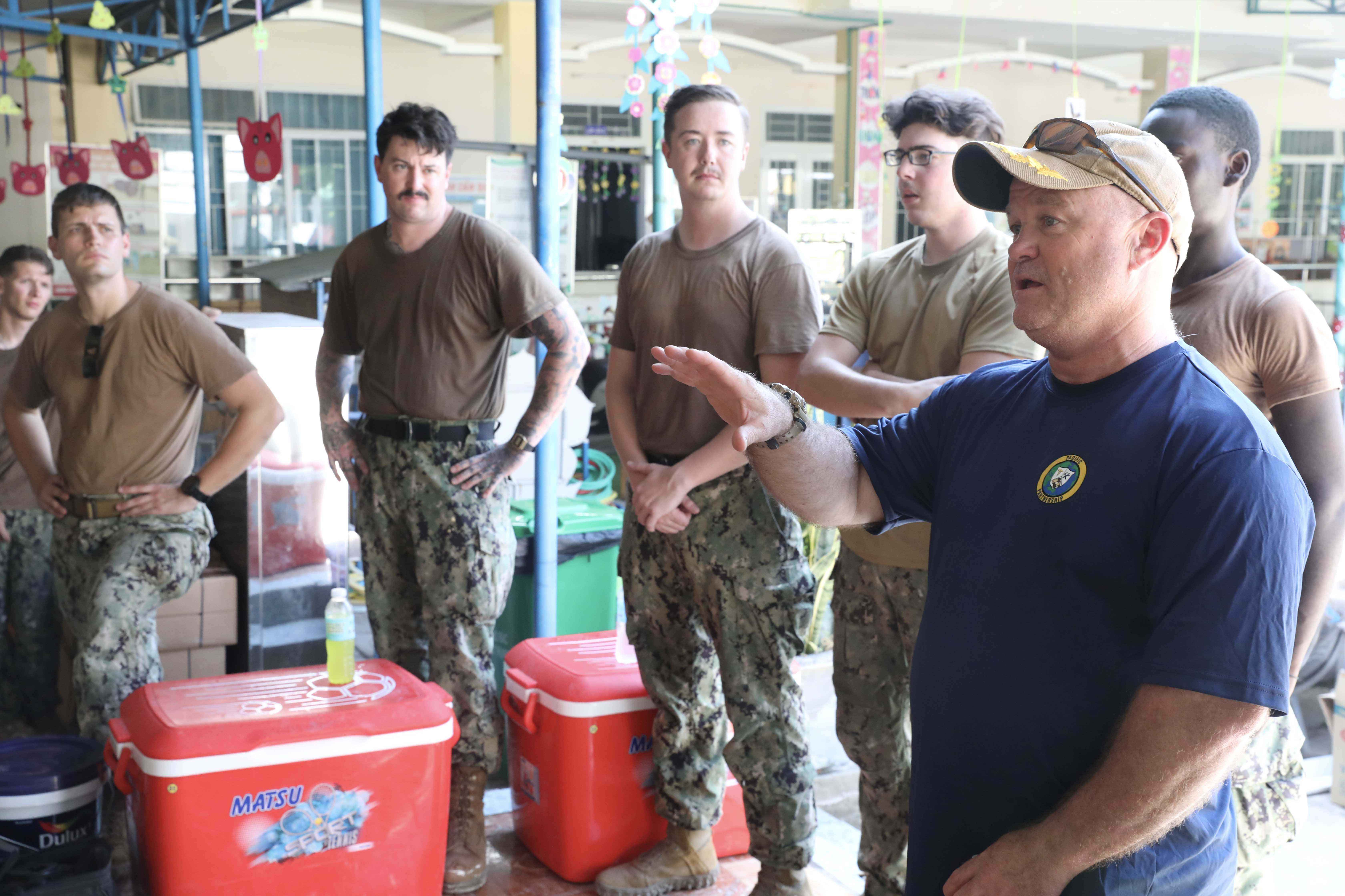 QUANG NGAI, Vietnam (Aug. 21, 2024) – Royal Australian Air Force Wing Cmdr. Scott Minchin, right, Pacific Partnership 2024-2 (PP24-2) deputy commander, speaks with service members from the U.S. and Australia at an engineering job site at Tinh Minh Nursery School in Quang Ngai, Vietnam, Aug. 21, 2024. Tinh Minh Nursery School is one of four multinational engineering projects for PP24-2 and Pacific Angel 2024-3 in Quang Ngai. Now in its 20th iteration, the Pacific Partnership series is the largest annual multinational humanitarian assistance and disaster relief preparedness mission conducted in the Indo-Pacific. Pacific Partnership works collaboratively with host and partner nations to enhance regional interoperability and disaster response capabilities, increase security and stability in the region, and foster new and enduring friendships in the Indo-Pacific. (U.S. Navy photo by Mass Communication Specialist 1st Class Ryan D. McLearnon/Released)
