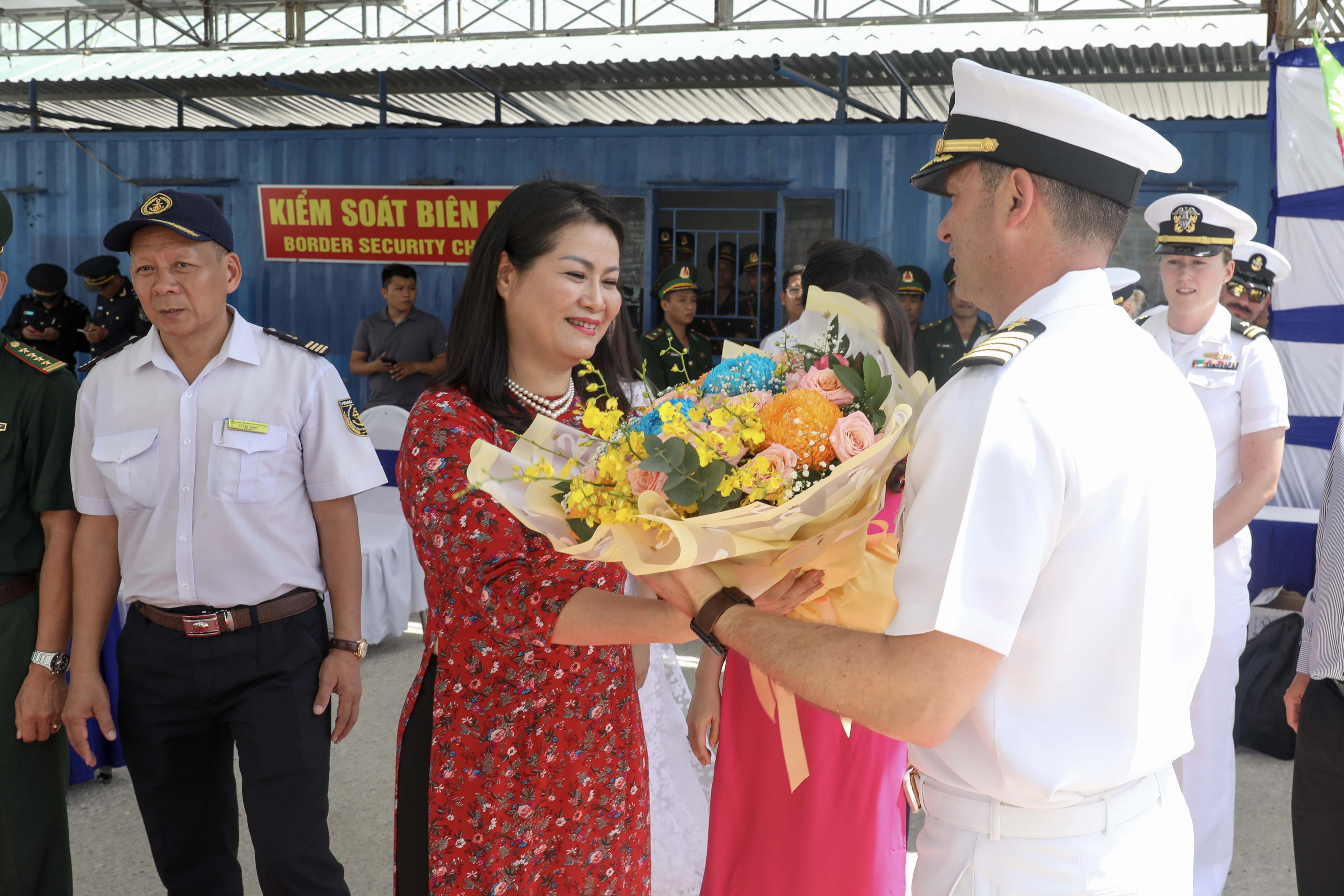 QUANG NGAI, Vietnam (Aug. 19, 2024) - Mrs. Ngo Thi Hoa, left, a representative from the Vietnamese Department of Foreign Affairs, greets U.S. Navy Capt. Daniel Keeler, Pacific Partnership 2024-2 (PP24-2) mission commander with a bouquet of flowers on the pier as the expeditionary fast transport ship USNS City of Bismarck (T-EPF 9) and the PP24-2 team arrive for a mission stop as part of PP24-2 in Quang Ngai, Vietnam, Aug. 19, 2024. Now in its 20th iteration, the Pacific Partnership series is the largest annual multinational humanitarian assistance and disaster relief preparedness mission conducted in the Indo-Pacific. Pacific Partnership works collaboratively with host and partner nations to enhance regional interoperability and disaster response capabilities, increase security and stability in the region, and foster new and enduring friendships in the Indo-Pacific. (U.S. Navy photo by Mass Communication Specialist 1st Class Ryan D. McLearnon/Released)