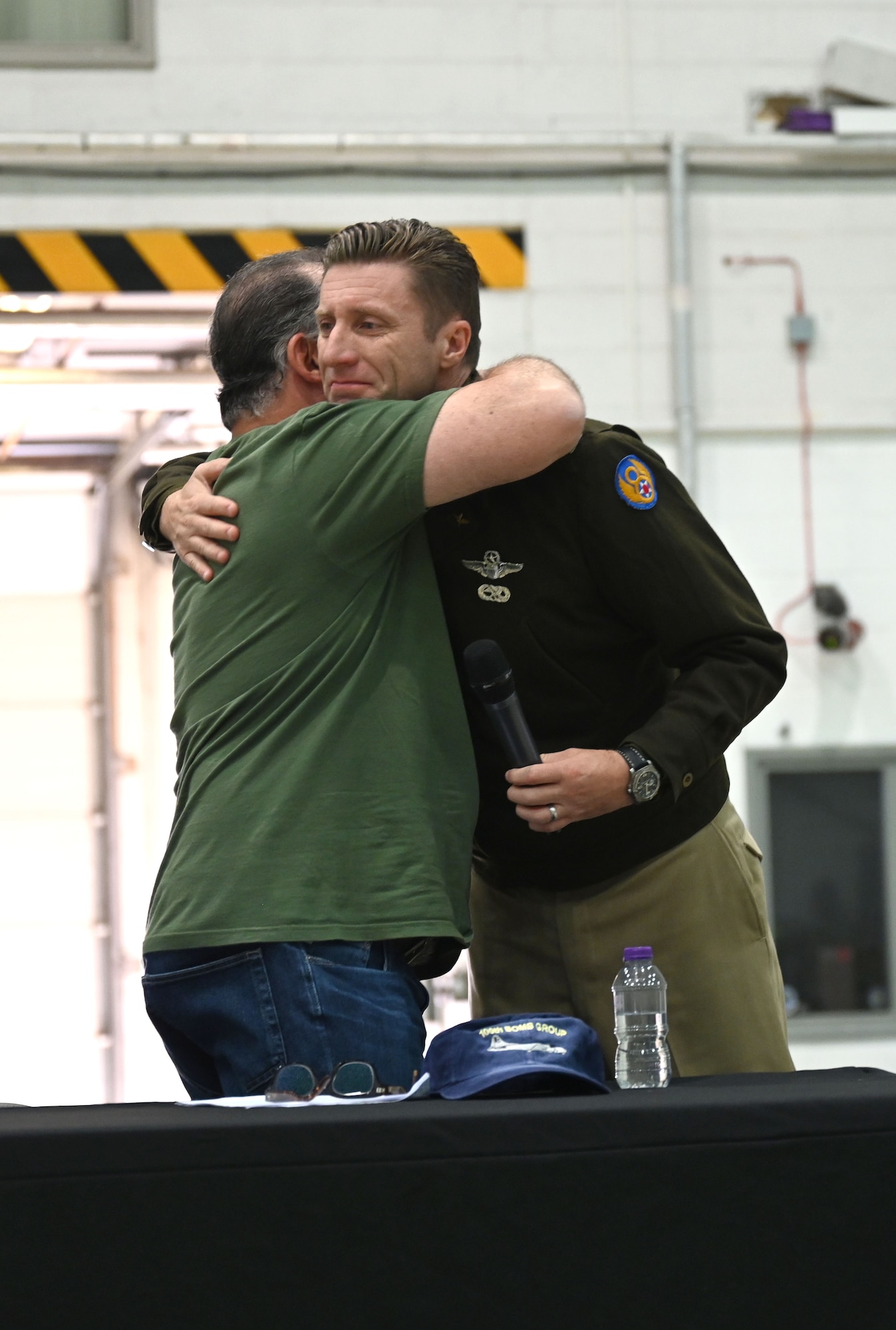 Dan Rosenthal, left, 100th BG Foundation board of directors member and son of U.S. Army Air Forces Lt. Col. Robert “Rosie” Rosenthal, renowned100th Bomb Group pilot who flew 53 missions out of Thorpe Abbotts, England, during World War II, gives an emotional hug to U.S. Air Force Col. Ryan Garlow, 100th Air Refueling Wing commander and step-grandson of T/Sgt James P. Scott, 351st Bomb Squadron and 100th BG radio-operator gunner, after a presentation at the Heritage Day event at Royal Air Force Mildenhall, England, Aug. 17, 2024. The base welcomed family members of 100th BG veterans who shared stories of their fathers’ time serving during World War II. (U.S. Air Force photo by Karen Abeyasekere)