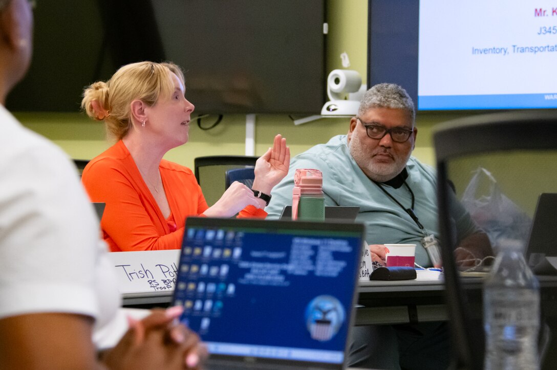 A woman speaks to a group of people sitting at a table.