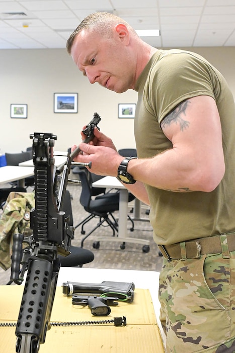 U.S. Air Force Master Sgt. Joshua Eby, the weapons section chief with the 127th Aircraft Maintenance Squadron, Michigan National Guard, removes a bolt from an M-249 light machine gun at Selfridge Air National Guard Base, Michigan, May 15, 2024. Members of the 127th Security Forces Squadron familiarized a small group of maintainers with the M-249 as part of Air Force training requirements and to prepare them to operate outside the wire, in contested environments.