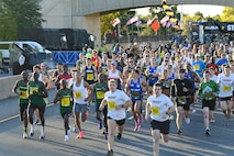 Hundreds of runners are running down a street during the Army Ten-Miler race.