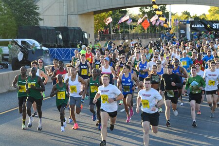 Hundreds of runners are running down a street during the Army Ten-Miler race.