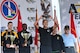 The men's division winners of the 39th annual Army-Ten Miler race hold their trophies in front of them on a stage as they are recognized. In the background are Army and race representatives dressed in casual attire.