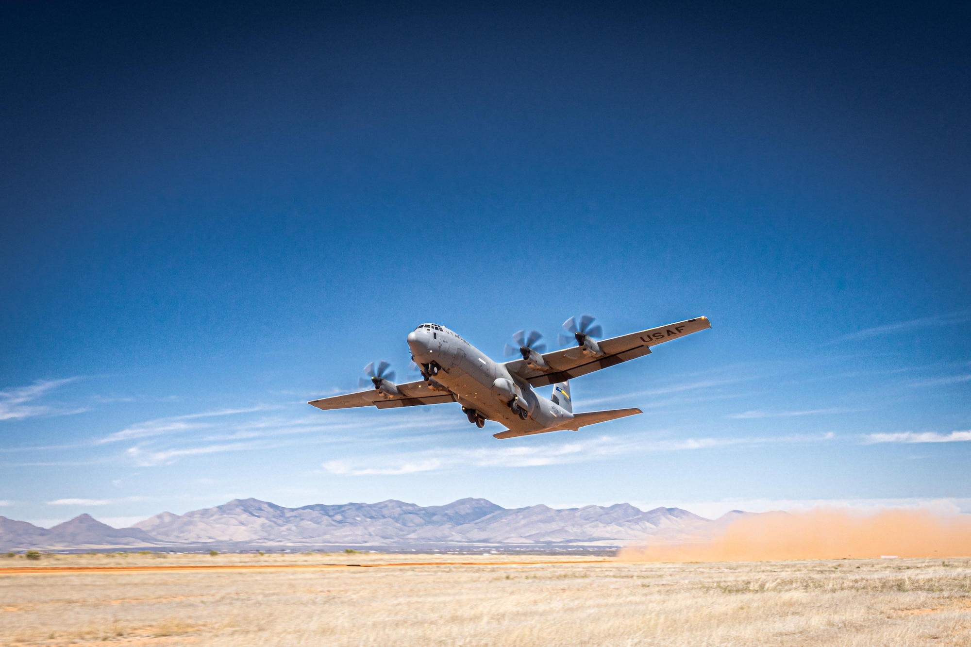 A C-130 flies above a landing zone.